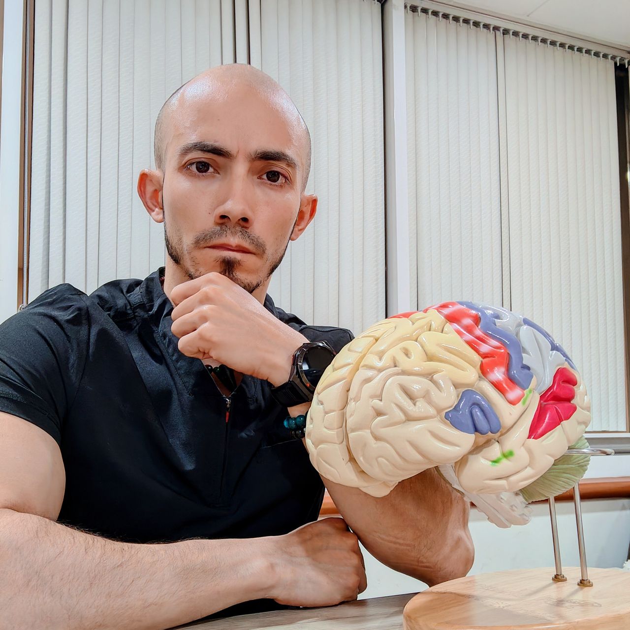 Dr. Diego Gabriel Torres Romo en su consultorio, sosteniendo un modelo anatómico del cerebro
